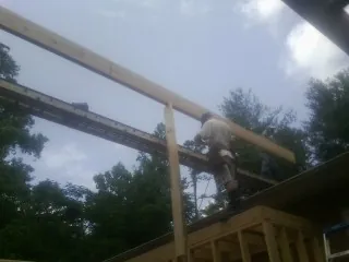 Carpenter setting a ridge beam over a new addition frame — Ice Dam Removal by Roofing Brothers in Springdale